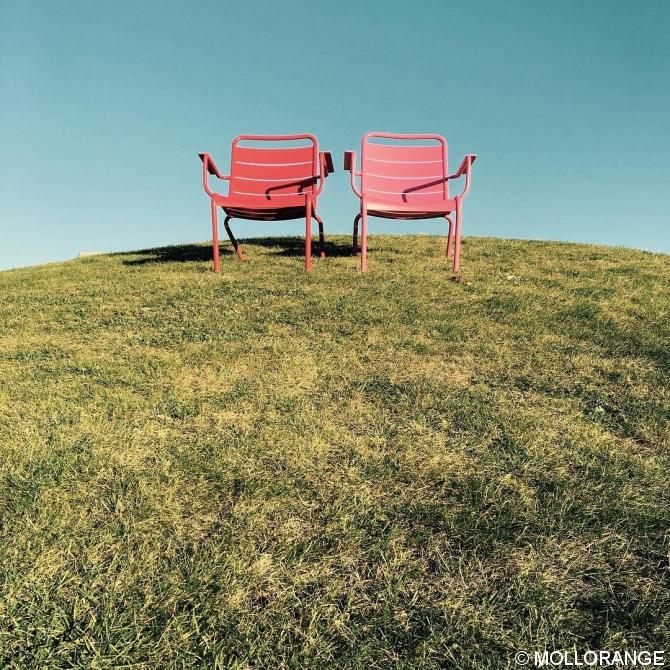 Die zwei roten Stühle auf dem  grünen Hügel.